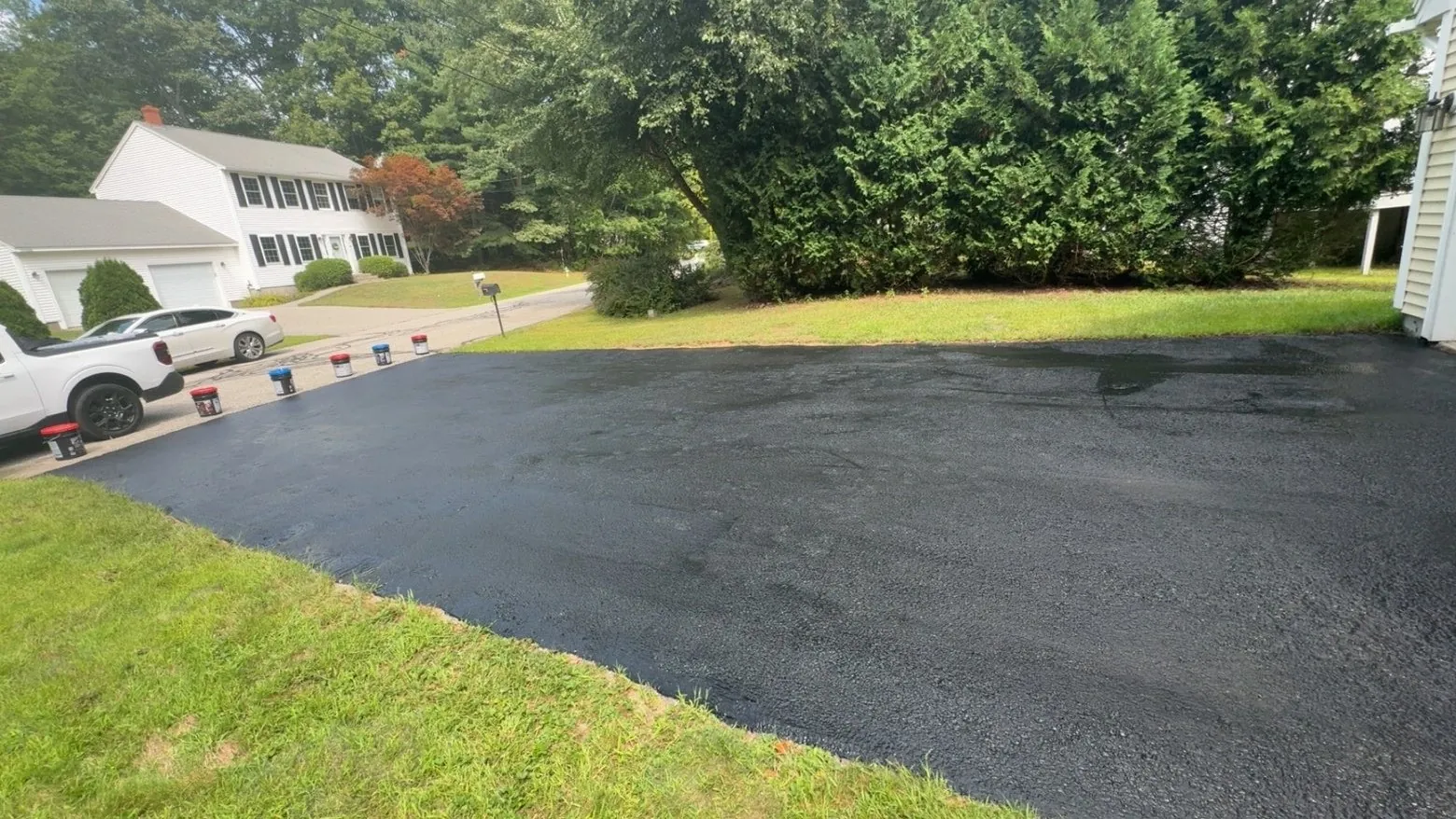 Freshly sealed driveway beside a green lawn