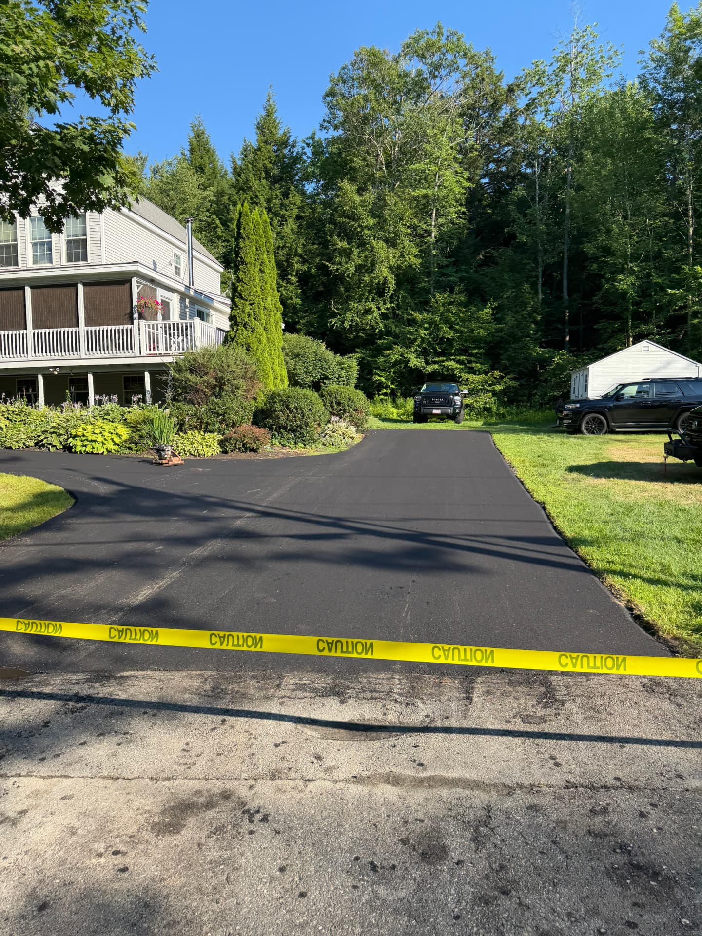 Newly paved driveway apron taped off with caution tape at the street