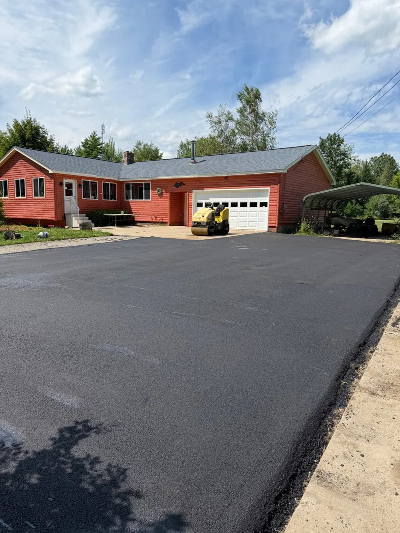 New asphalt driveway in front of a two-car garage with roller