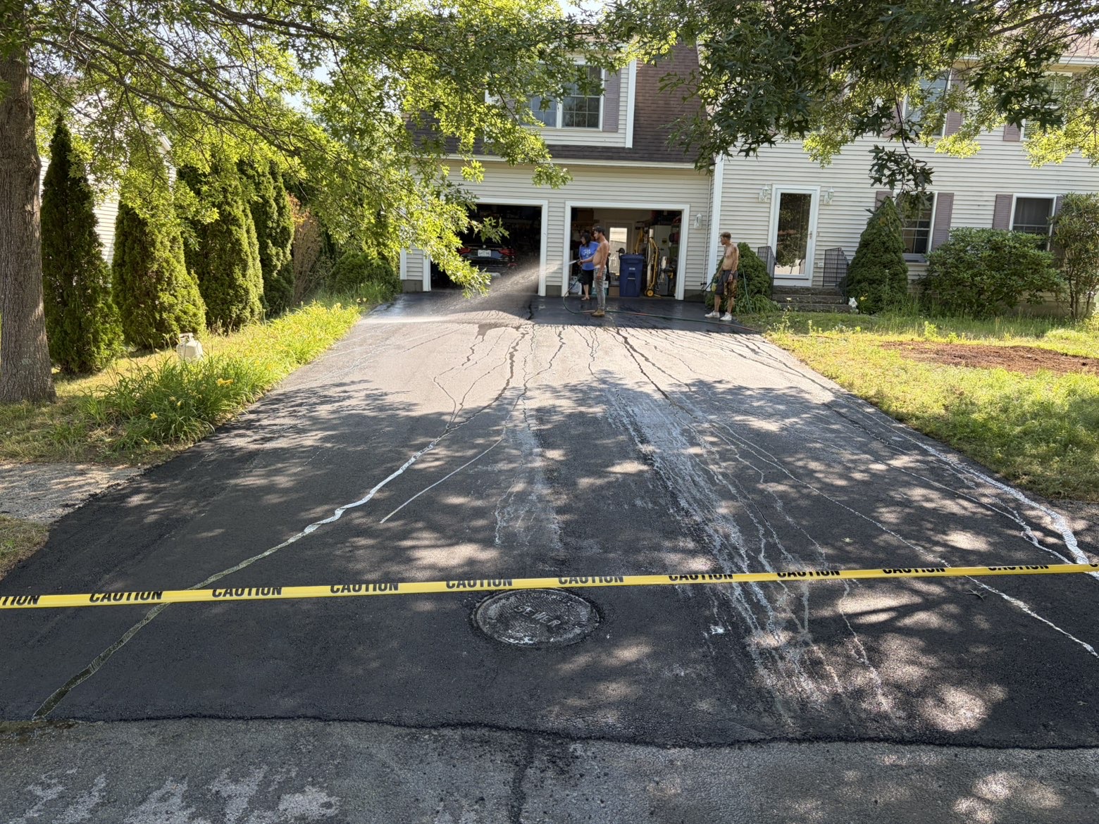 Sealcoated driveway with caution tape while the fresh sealer cures